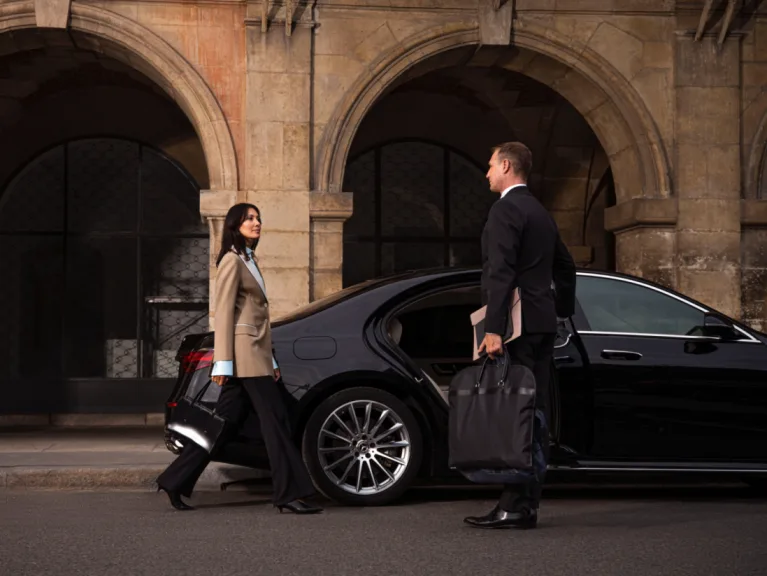 Chauffeur empfängt eine Geschäftsfrau an einer schwarzen Limousine